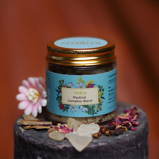 Nytarra Mystical Camphor Blend in a glass jar with a gold lid, surrounded by camphor crystals, dried petals, and spices.