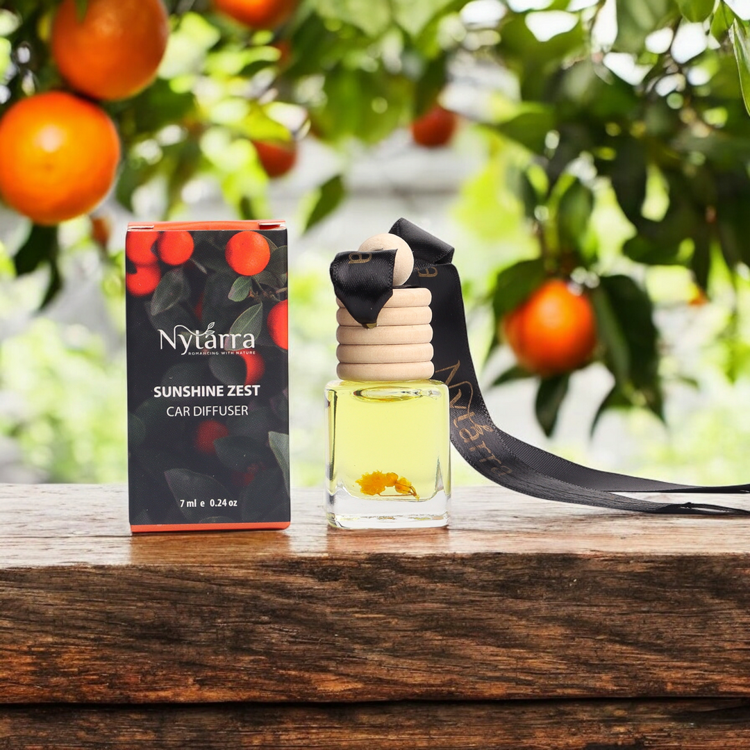 Nytarra Sunshine Zest car diffuser with a citrus-inspired design, featuring a yellow-tinted fragrance bottle with floral elements and a black ribbon, set against a backdrop of fresh orange trees.